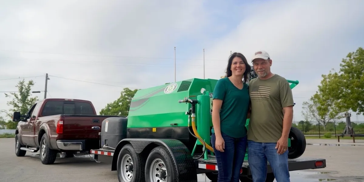 A man and woman standing in front of a green truck.